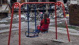Дівчинка на дитячому майданчику біля зруйнованого російськими бомбами будинку. ФОТО ДНЯ