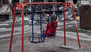 Дівчинка на дитячому майданчику біля зруйнованого російськими бомбами будинку. ФОТО ДНЯ