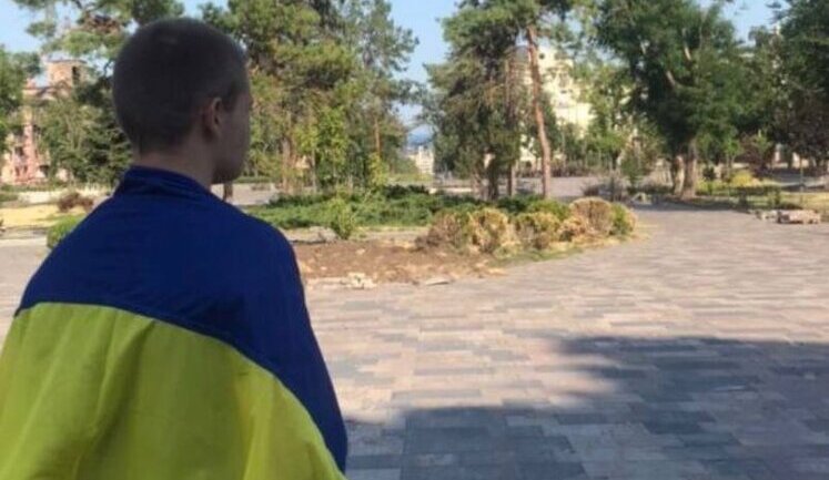 Young man with flag of Ukraine went to square near bombed-out Mariupol Drama Theater. PHOTO