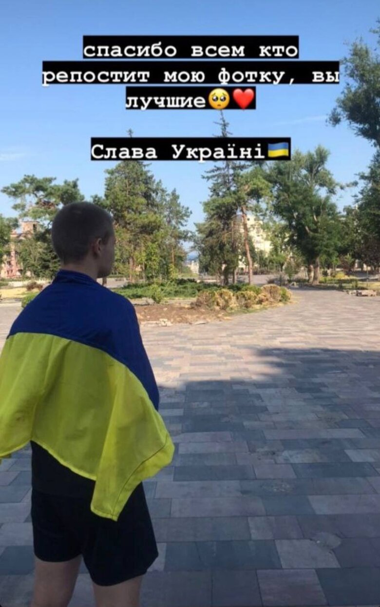 Young man with flag of Ukraine went to square near bombed-out Mariupol Drama Theater 01
