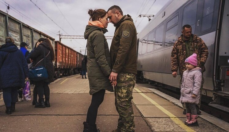 On front page of New York Times is photo of border guard saying goodbye to his family in Kramatorsk. PHOTO