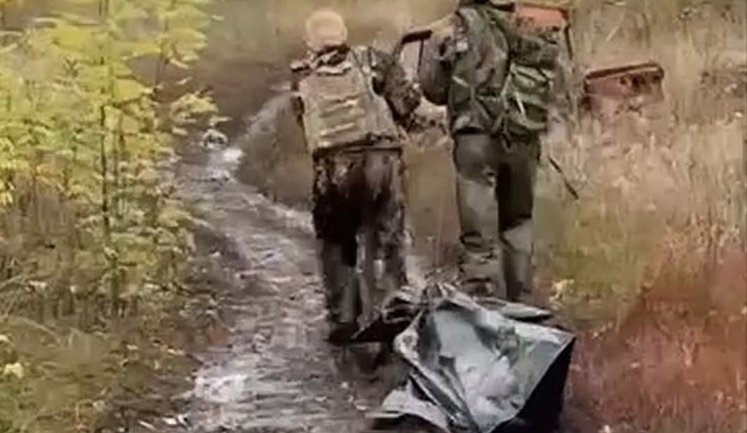 Two occupiers drag their "KIA" in black bag along a field road: "Didn’t quite make it. May he rest in heaven.". VIDEO