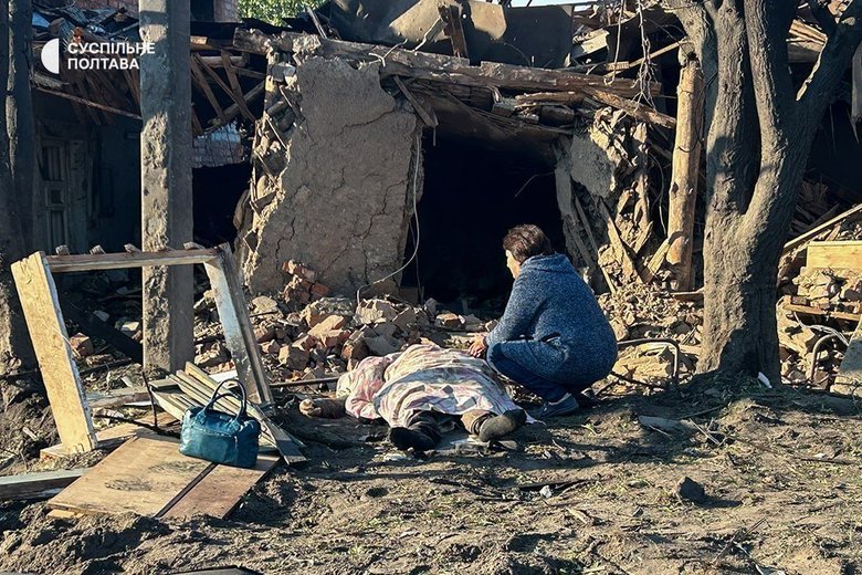 A woman sits beside the body of her deceased son in Kremenchuk