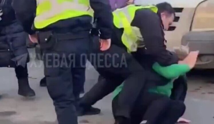 In Odesa, police officer knocked woman down, put her face to ground and pin back her arms during conflict in street. VIDEO