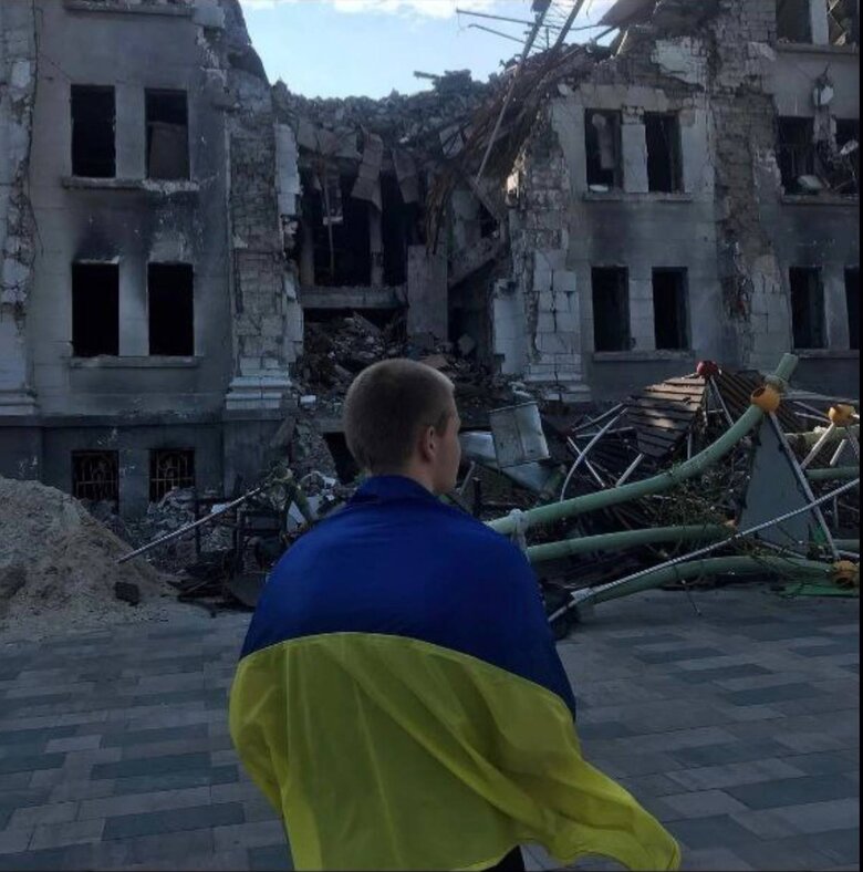 Young man with flag of Ukraine went to square near bombed-out Mariupol Drama Theater 02