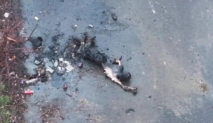 Burnt and mutilated body of Russian invader lying on road. VIDEO
