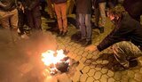 Протестующие под Офисом Президента греются от горящего полицейского шлема. Фото дня