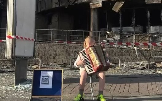 Підліток грає на акордеоні на тлі зруйнованого ТЦ на Лук’янівці композицію "Як тебе не любити, Києве мій!". ВIДЕО