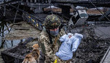 Український воїн переносить немовля через руїни. ВРАЖАЮЧЕ ФОТО