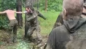П’ятеро окупантів лупцюють палицями свого напівголого поплічника, розіп’ятого між двох дерев. ВIДЕО