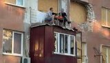 двое херсонцев сидят на разрушенном балконе